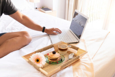 Working on a laptop while having pancakes on bed