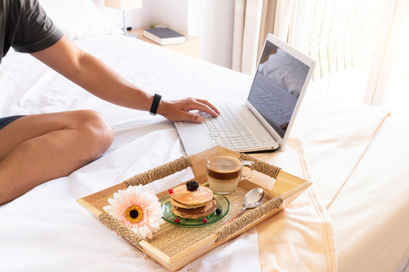 Working on a laptop while having pancakes on bed
